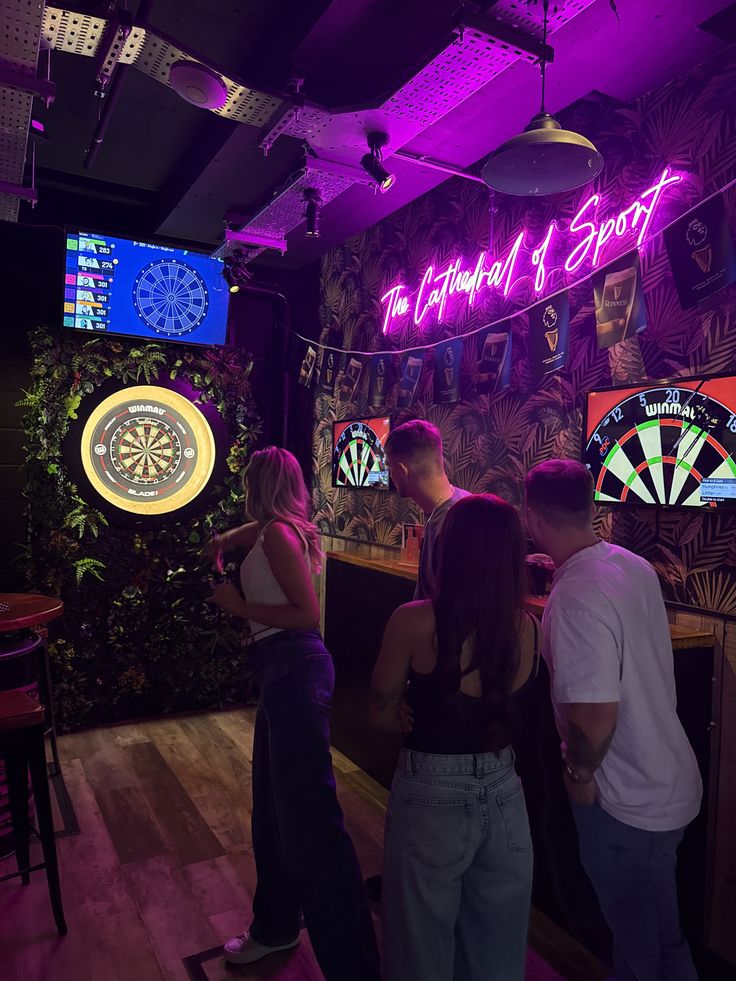 Friends playing darts in a neon lit bar